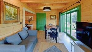 A cozy cabin interior with a sofa, dining table, chairs, and a TV. - Cozy home in Czaplinek with lake view (Czaplinek)