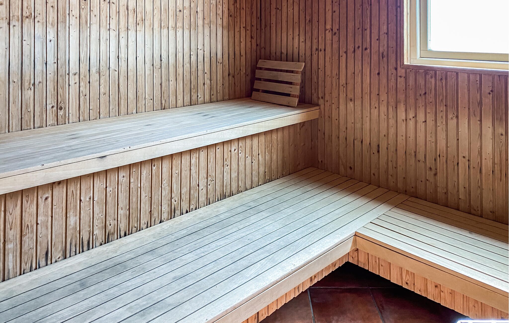 A wooden sauna with two benches and a window.