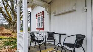 A white porch with a red-framed window, two black wicker chairs, and a small table. - Nice home in årjäng with WiFi (Årjäng)