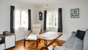 A room with a wooden dining table, a white chair, a sofa, and a small cabinet. - Nice home in årjäng with WiFi (Årjäng)