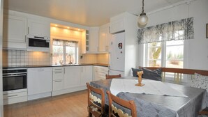 A kitchen with white cabinets, a microwave, an oven, and a sink. There is a dining table with a tablecloth and chairs. - Nice home in årjäng with WiFi (Årjäng)