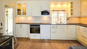 A modern kitchen with white cabinetry, a built-in oven, a dishwasher, and a large window with curtains. - Nice home in årjäng with WiFi (Årjäng)