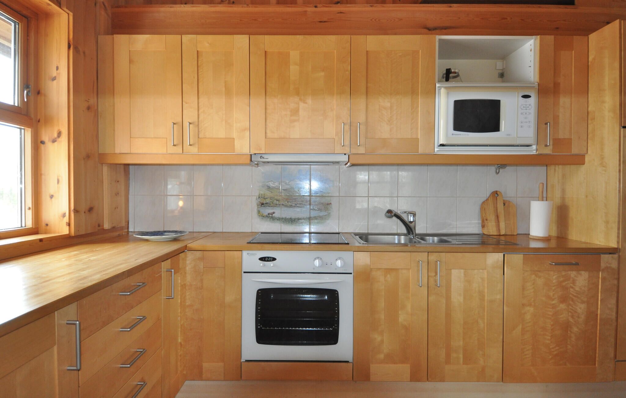 Une cuisine avec des meubles de rangement en bois, un four à micro-ondes, une cuisinière et un évier.