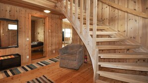 A wooden interior with a staircase, a bed, a chair, and a fire extinguisher. - Beautiful home in Koppom with sauna (Koppom)