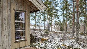 A wooden cabin with a large window, surrounded by a snowy forest. - Beautiful home in Koppom with sauna (Koppom)