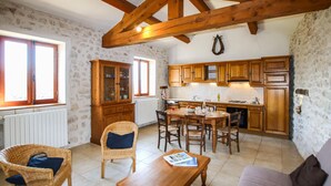 Una cocina acogedora con armarios de madera, una mesa de comedor y una silla de mimbre.
