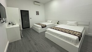 A hotel room with two beds, a desk, a chair, a TV, and a door. - Aure Residence Hotel (Sihanoukville)