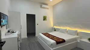 A modern hotel room with a large bed, bedside tables, a desk with a chair, a flat-screen TV, and an air conditioning unit. - Aure Residence Hotel (Sihanoukville)