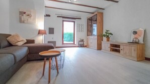 A living room with a sofa, a small round table, and a cabinet. There is a window with a view of greenery outside. - 2 bedroom pet friendly home in Treignes (Treignes)