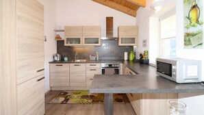 A modern kitchen with wooden cabinets, a stainless steel range hood, a built-in oven, a microwave, and a sink. - Ferienwohnung in Abtenau (Abtenau)