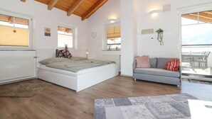 A spacious room with a bed, a sofa, and a dining area. - Ferienwohnung in Abtenau (Abtenau)
