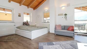 Een ruime kamer met een bed, een slaapbank en een eethoek.