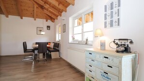 A cozy room with a wooden ceiling, a dining area with a bench and chairs, a radiator, and a vintage telephone on a dresser. - Ferienwohnung in Abtenau (Abtenau)