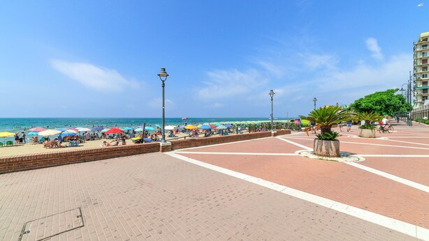A beach promenade with a brick walkway, umbrellas, and a palm tree. - Awesome apartment in Scarlino with WiFi (Scarlino)