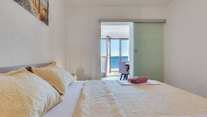 Ett hotellrum med en stor säng, ett skrivbord och utsikt över havet genom en skjutdörr.