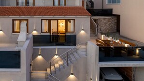 Ett modernt hus med ett matområde, en trappa och en bil parkerad utanför.