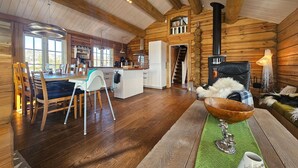 L’intérieur d’un chalet confortable en bois, avec un coin repas, une cuisine et une cheminée.