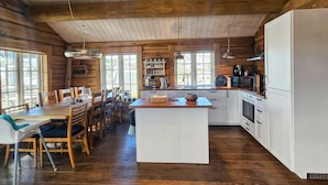 L’intérieur d’une cabane en bois comprend un coin repas, une cuisine et de grandes fenêtres.