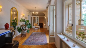 Ein Flur mit einer Chandelier, einer roten Vase und einem großen Spiegel.