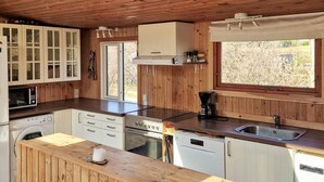 A compact kitchen with wooden cabinetry, a built-in oven, a microwave, and a coffee maker.