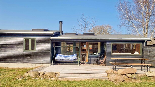 A cabin with a porch, a covered seating area, and a picnic table.