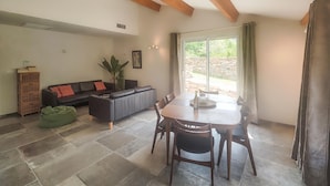 A spacious living area with a dining table, sofa, and a stone fireplace. - 3 bedroom stunning home in Vieussan (Vieussan)