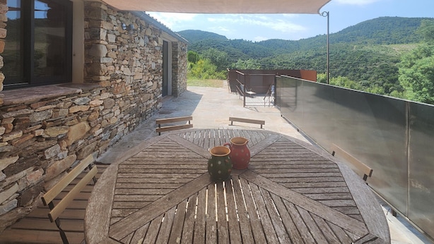A wooden table with two cups and a bench on a balcony with stone walls, overlooking a mountainous landscape. - 3 bedroom stunning home in Vieussan (Vieussan)