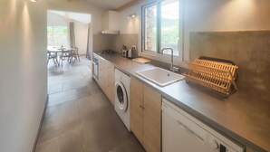 A modern kitchen with a washing machine, a sink, and a window overlooking greenery. - 3 bedroom stunning home in Vieussan (Vieussan)
