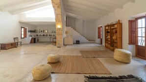 A spacious loft with high ceilings, a staircase, and a rustic decor including woven baskets and a wooden bookshelf.