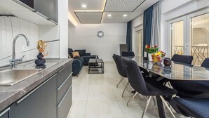 Uma cozinha moderna com pia embutida e área de jantar com mesa de vidro e cadeiras pretas.
