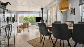 A modern dining area with a wooden table, grey upholstered chairs, and a woven light fixture.