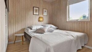 A bedroom with a bed, a small table, and a window with a view.