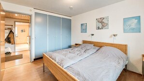 Un dormitorio con cama, armario y una obra de arte en la pared.