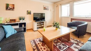 Una sala de estar con un sofá, una mesa de centro, un televisor y una ventana.