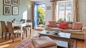 A living room with a sofa, a coffee table, a dining table with chairs, and a view of a garden through a door. - 2 bedroom beautiful home in Taden (Taden)