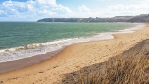 A beach with a sandy shore, waves, and a distant cliff. - 2 bedroom beautiful home in Taden (Taden)