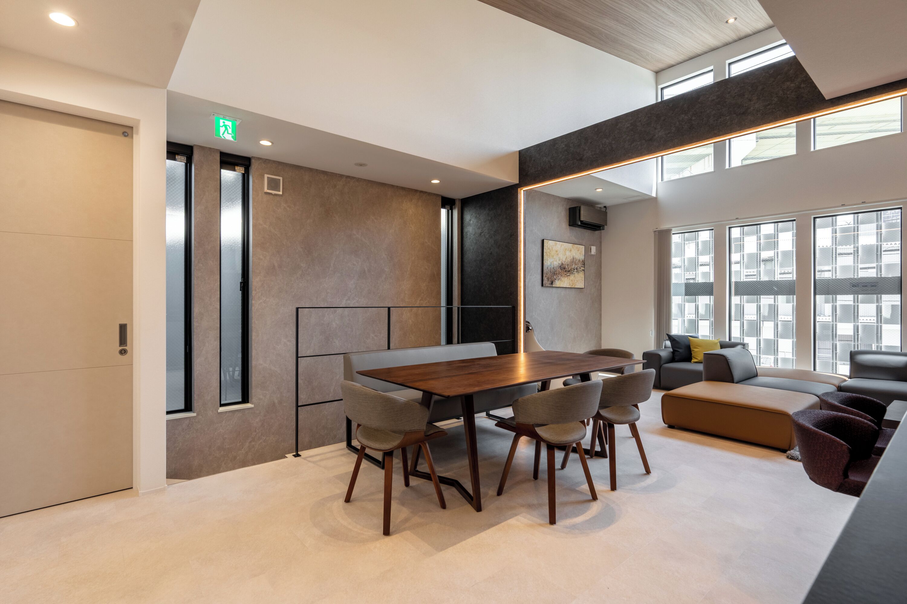 A modern conference room with a wooden table, chairs, and a large mirror.