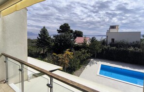 A balcony with a glass railing overlooking a swimming pool, a red-roofed house, and a mountainous landscape. - Luxurious home in Kastel Stafilic (Kastel Stafilic)