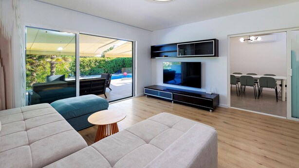 A modern living room with a large TV, a sofa, a coffee table, and a dining area visible through a glass door. - Luxurious home in Kastel Stafilic (Kastel Stafilic)