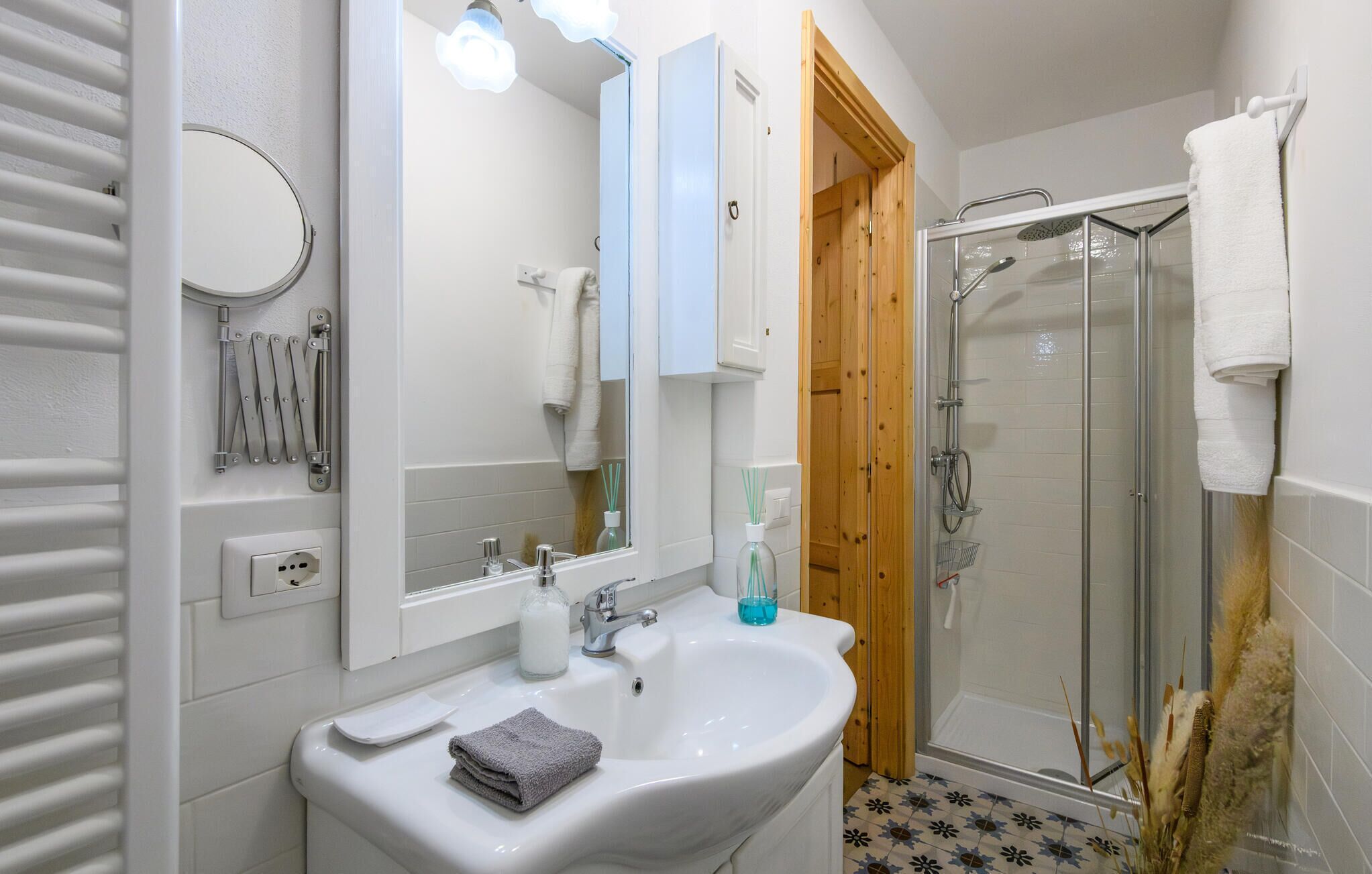 Een badkamer met een wit wastafelmeubel, spiegel en douche.