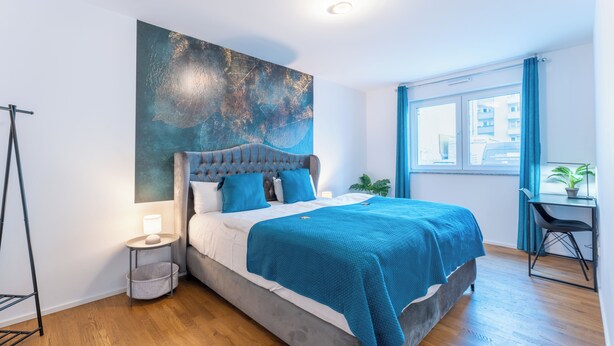 Een moderne slaapkamer met een groot bed, een bureau en een raam met gordijnen.