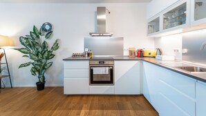 Een moderne keuken met een ingebouwde oven, een roestvrijstalen afzuigkap en een potplant.