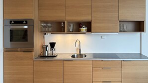 Een moderne keuken met houten kasten, een inbouwoven, een koffiezetapparaat en een spoelbak.