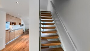 Een moderne keuken met houten kasten en een houten trap naar een hoger niveau.