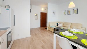 A modern kitchen with a built-in oven and a dining area with a table set for four. - Nice apartment in Koszalin with WiFi (Koszalin)