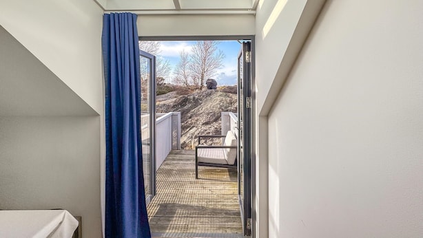 Een smalle gang die uitkomt op een balkon met uitzicht op een rotsachtig landschap.
