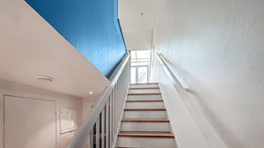 Een trap met witte muren en een blauw plafond, die leidt naar een kamer met een raam.