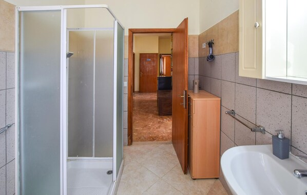 A bathroom with a shower, a sink, and a toilet.