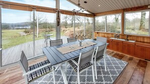 A dining area with a table and chairs, large windows, and a view of the outdoors.