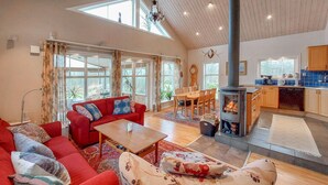 A spacious living area with a red sofa, a wooden dining table, and a fireplace.